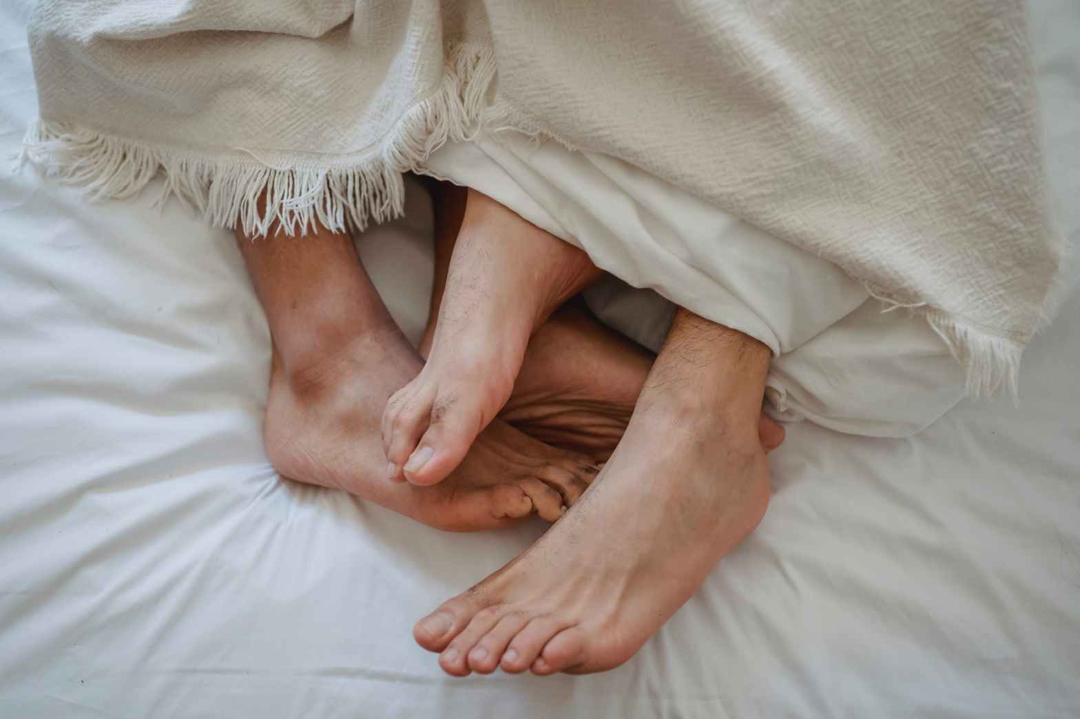 close up of mens feet intertwined in bed
