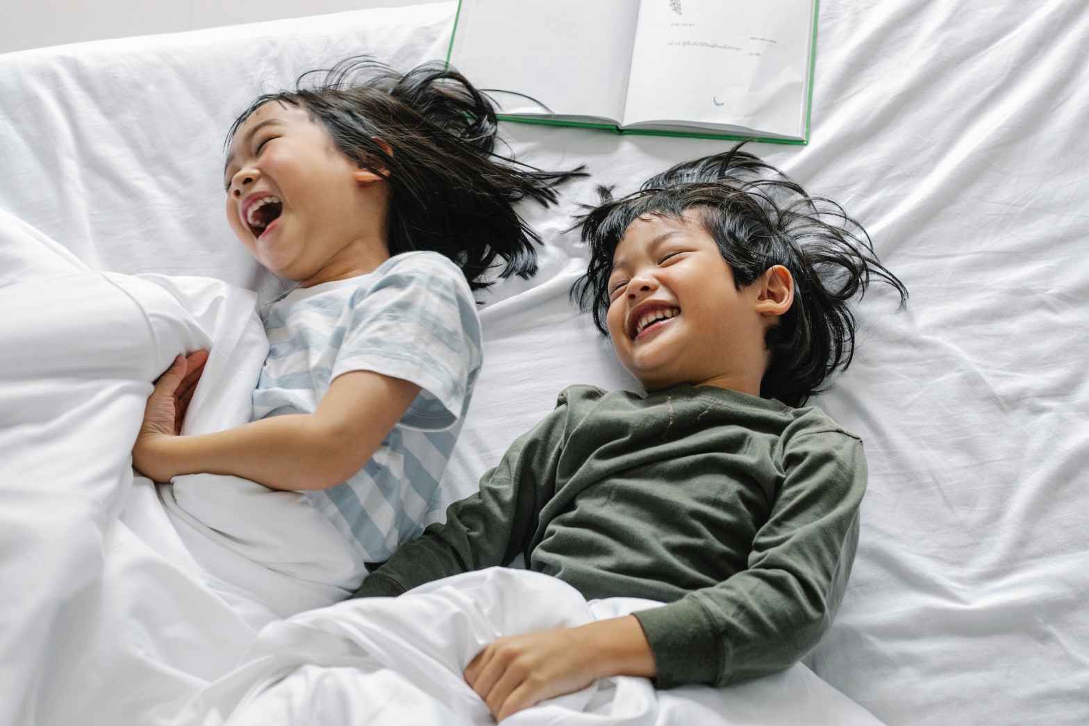 cheerful asian kids having fun in bed