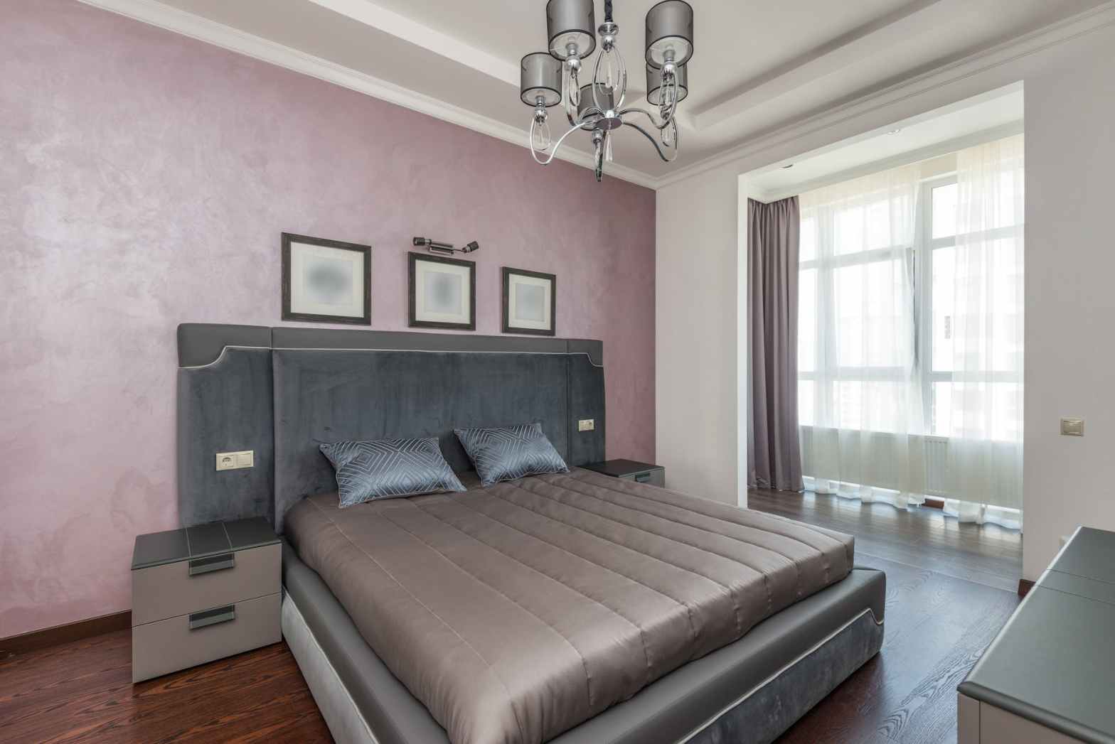 a cozy bed with chandelier hanging on the ceiling